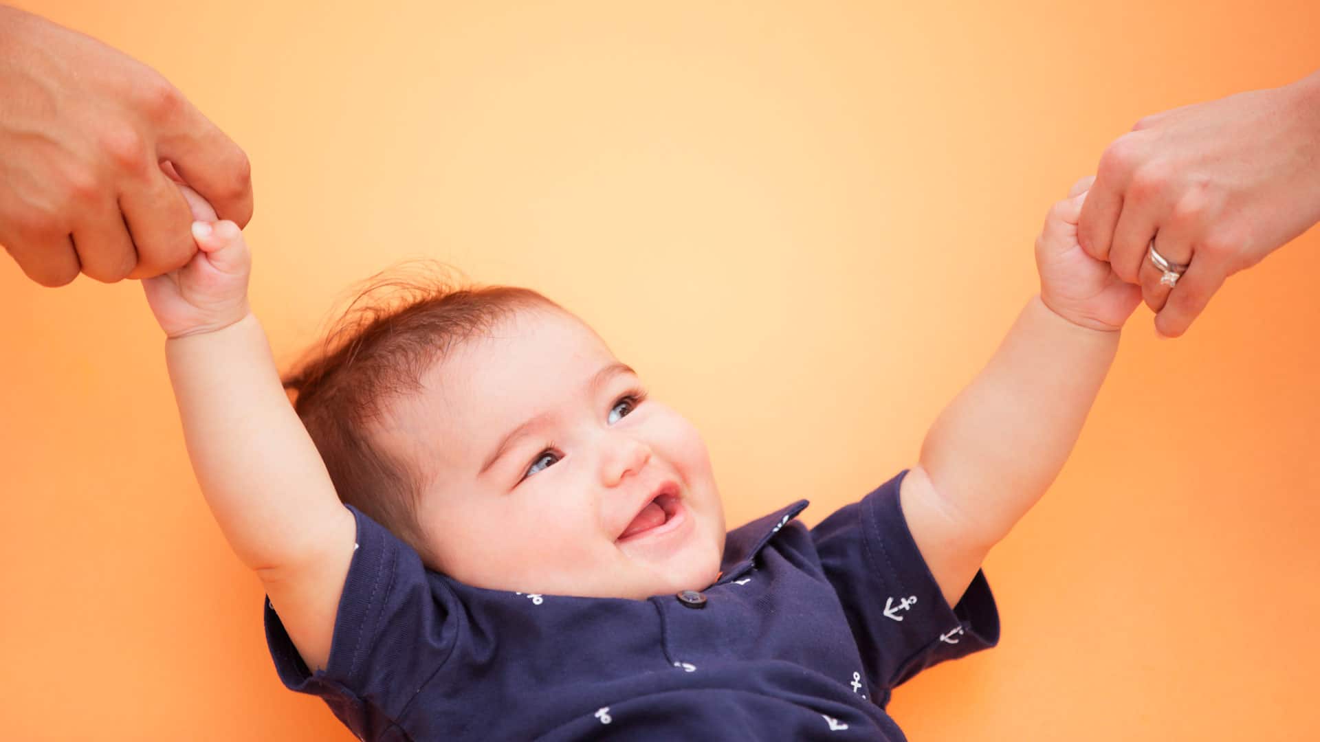 bebe dando as mãos para os pais imunodeficiências congênitas
